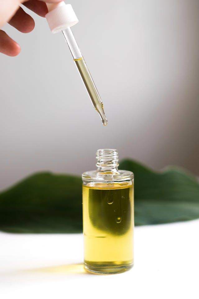 Pipette huile vitamine D3 au-dessus d'un flacon rempli d'huile avec feuille verte en arrière-plan