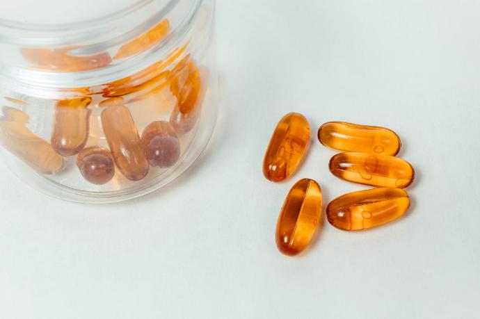 Gélules oranges compléments alimentaires dans bocal transparent et à côté