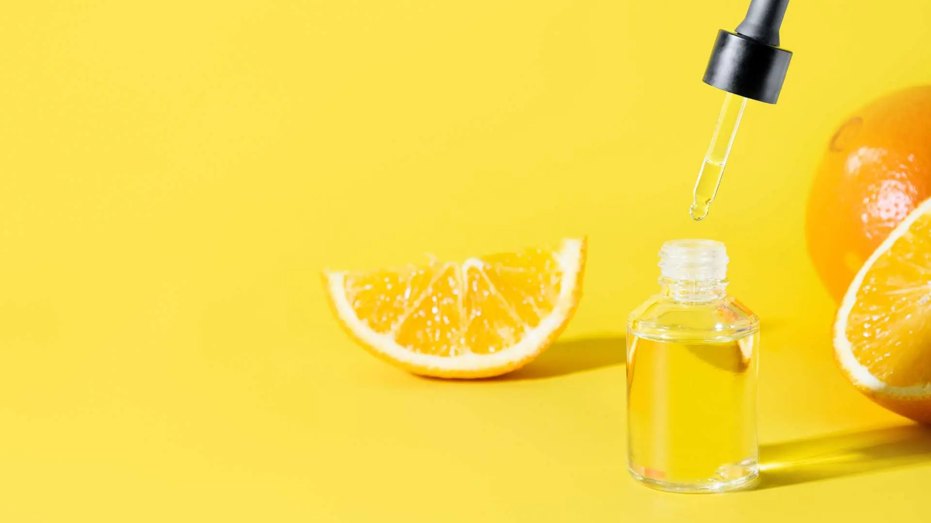 Oranges avec vitamine C liquide en flacon sur  fond jaune