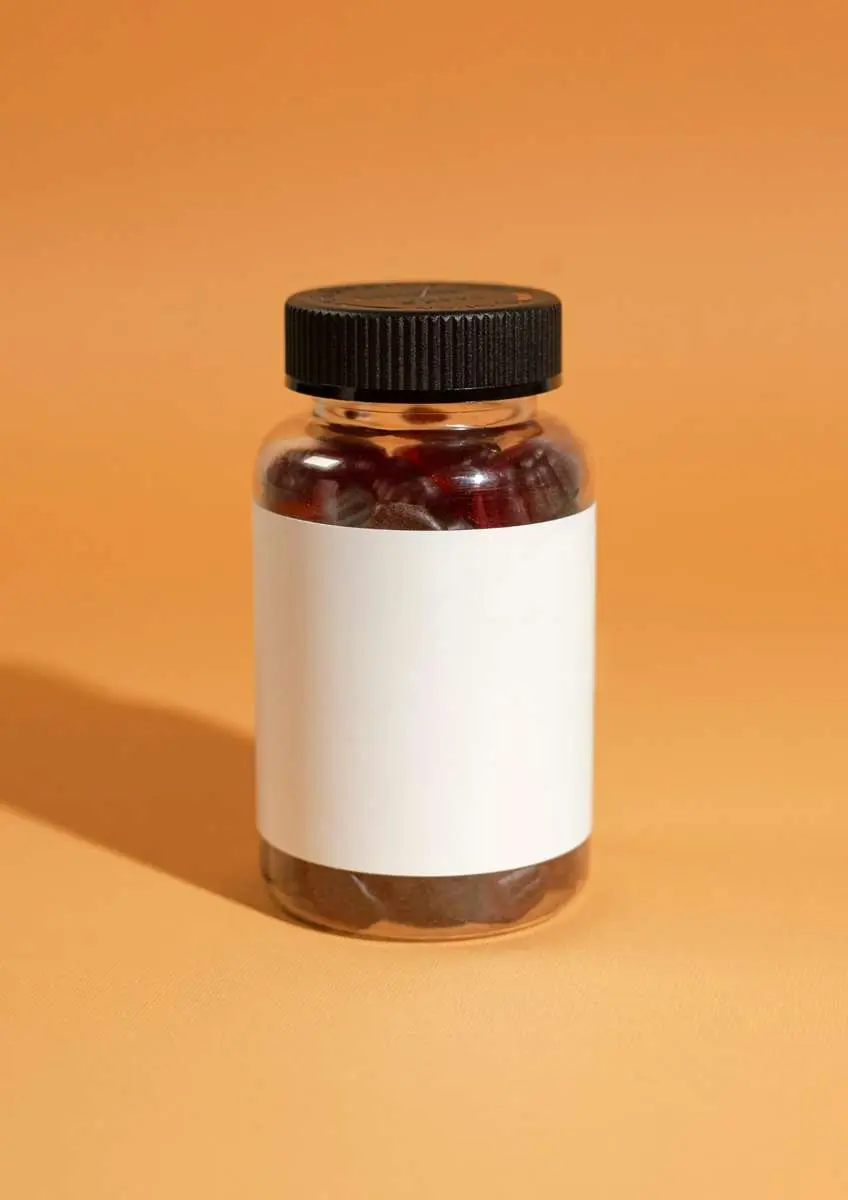 Flacon de compléments alimentaires avec étiquette blanche vierge sur fond orangé avec ombre flacon