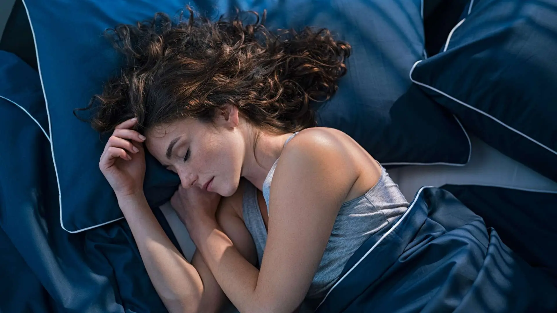Femme qui dort sur le côté dans des draps bleus